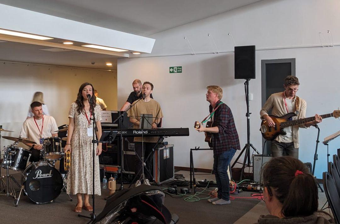 A photo of Meraki performing, a worship group with guitarists, singers, a drummer and keyboard player