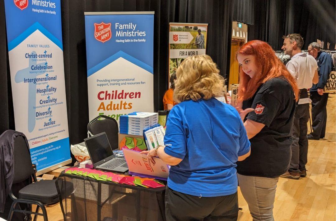 A photo of two people looking at resources and talking at the Family Ministries stand in the marketplace