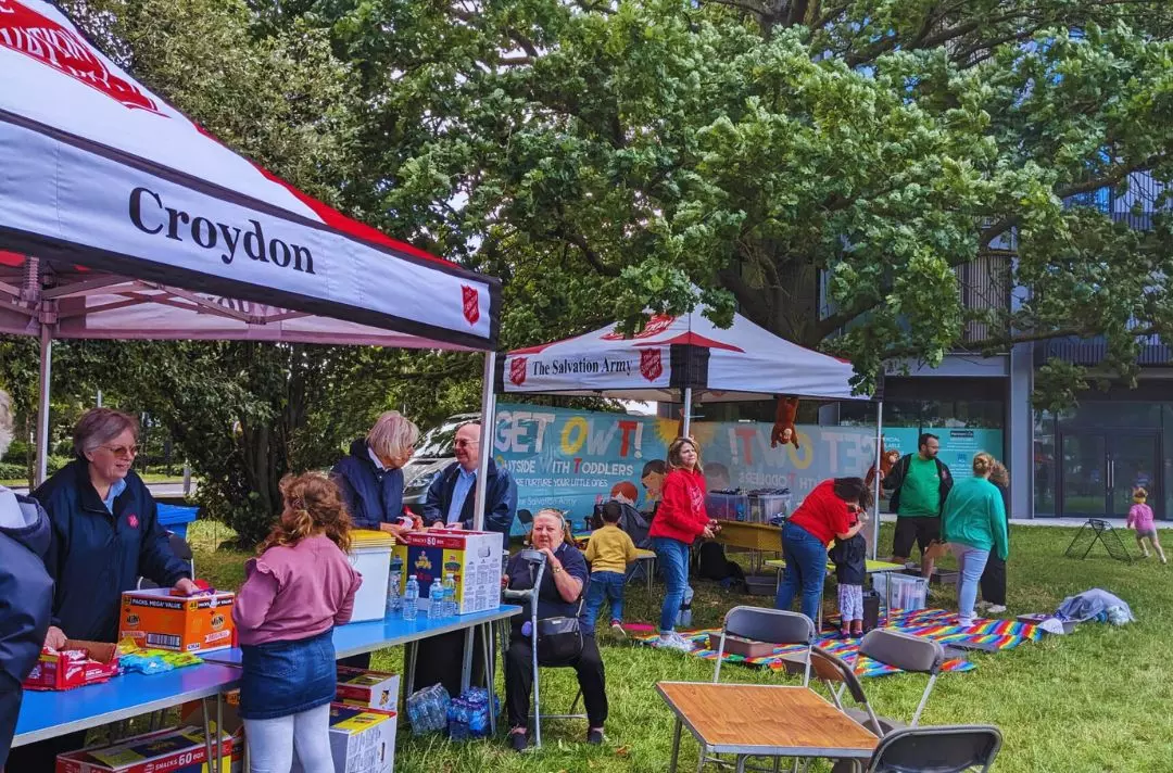 A photo of two Salvation Army gazebos in a park with people of all ages socialising