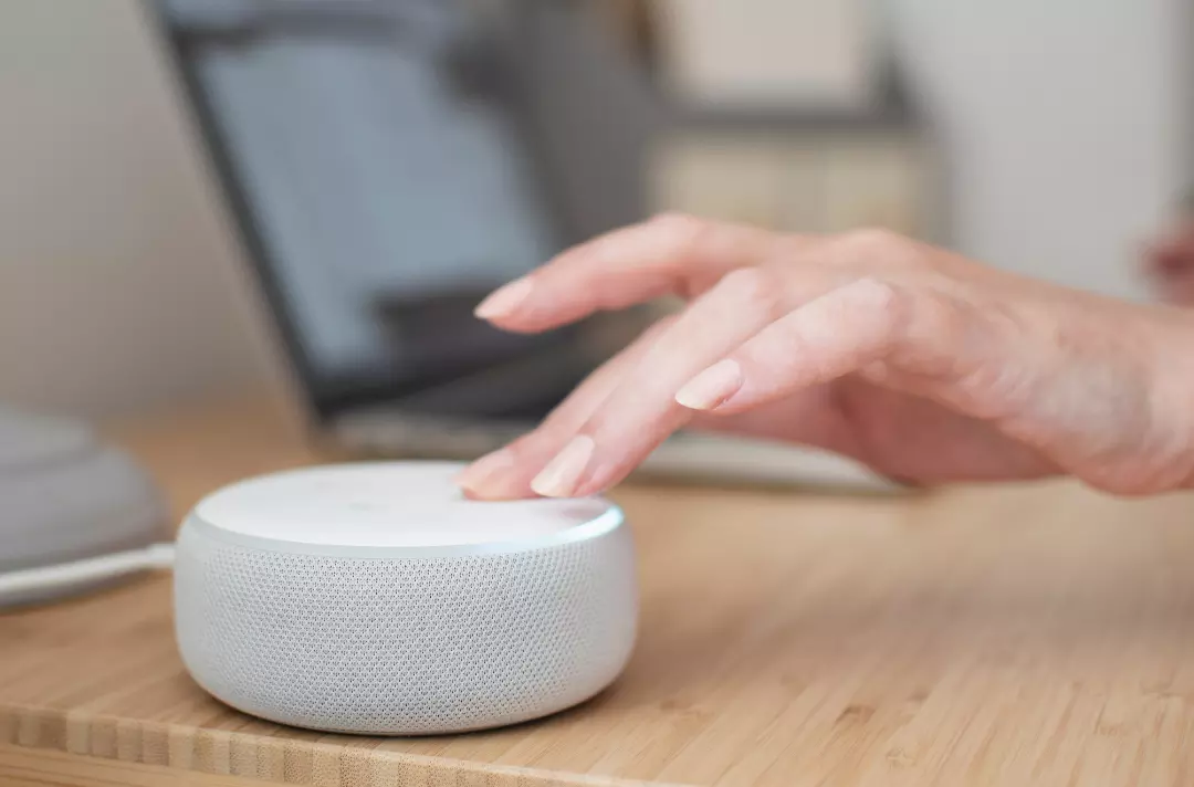 Photo shows an older person touches an Alexa device to activate it.