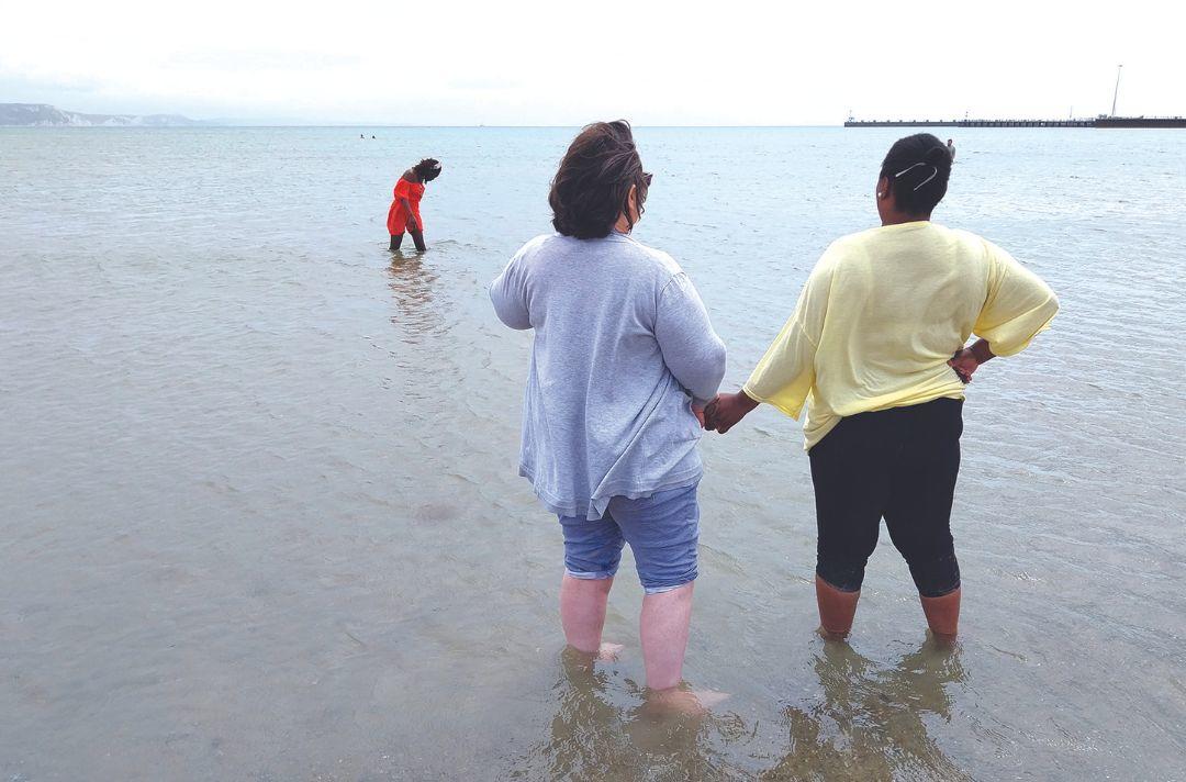 A photo of two women holding hands in the sea