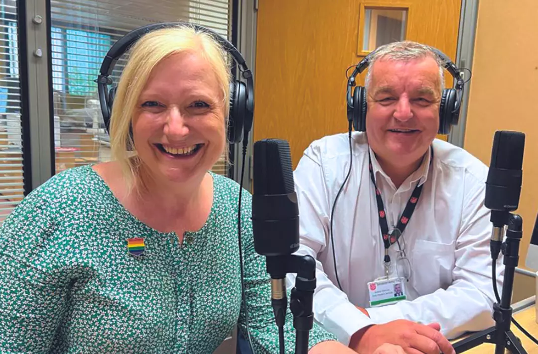 A photo shows Ali and Andy smiling broadly at the camera while sat in front of recording equipment.