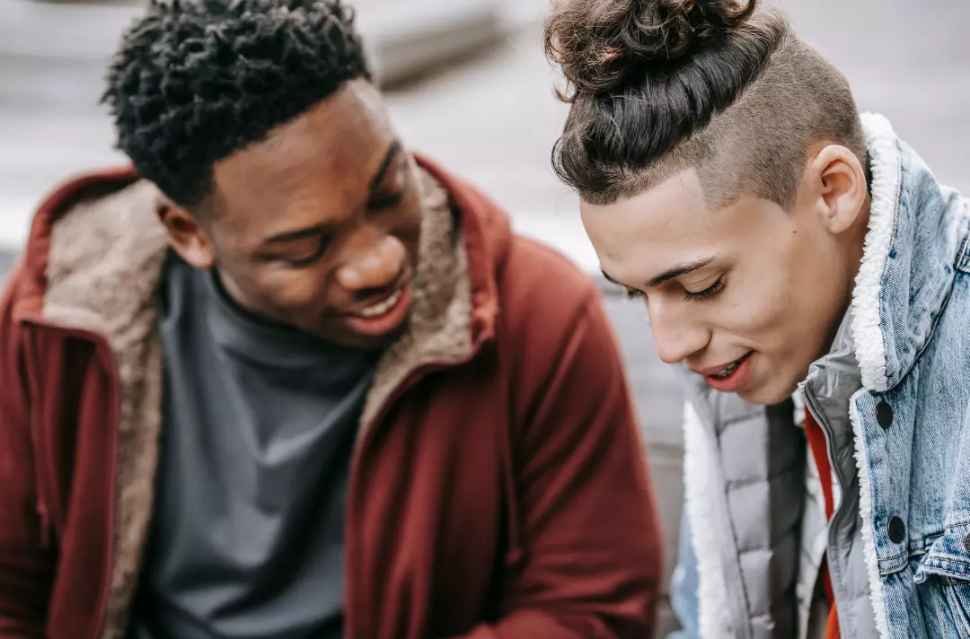 A photo shows two people sat close to each other who are talking and smiling.