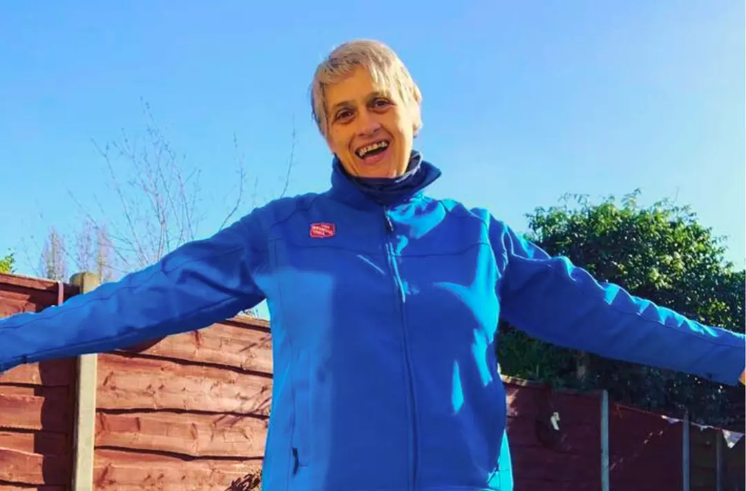 A photo shows Estelle Blake smiling with her arms spread wide.