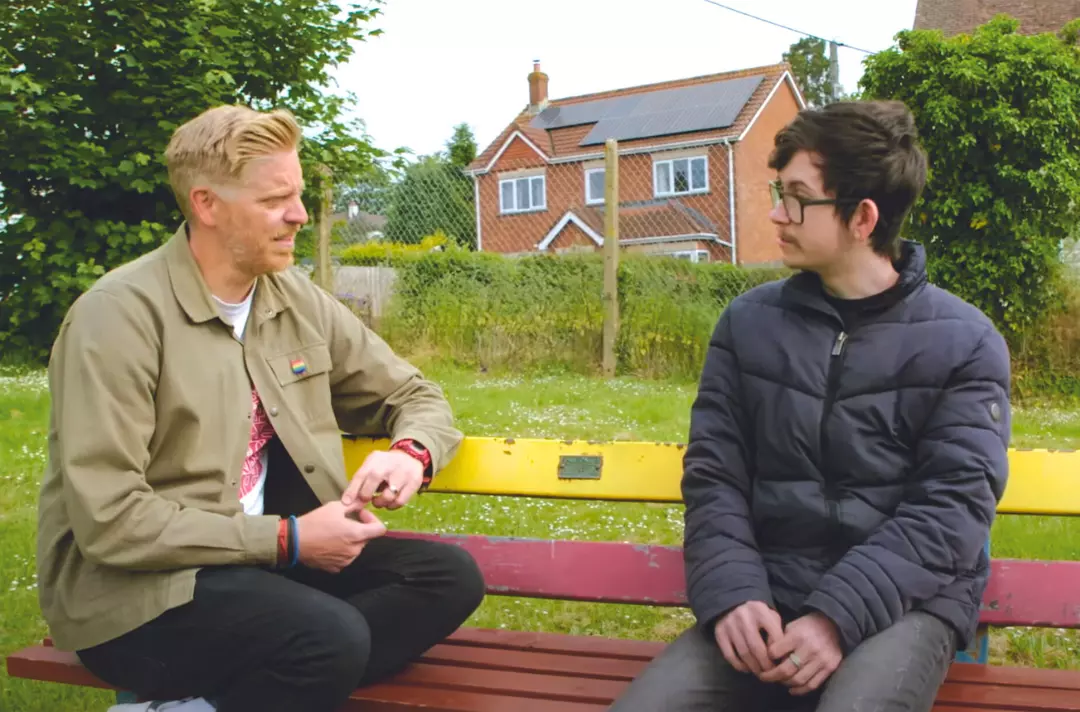 A photo shows a mentor talking to a student on a park bench.