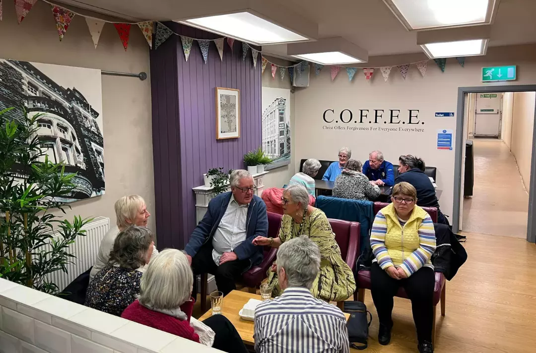 A photo shows people sitting together and engaging in conversation.
