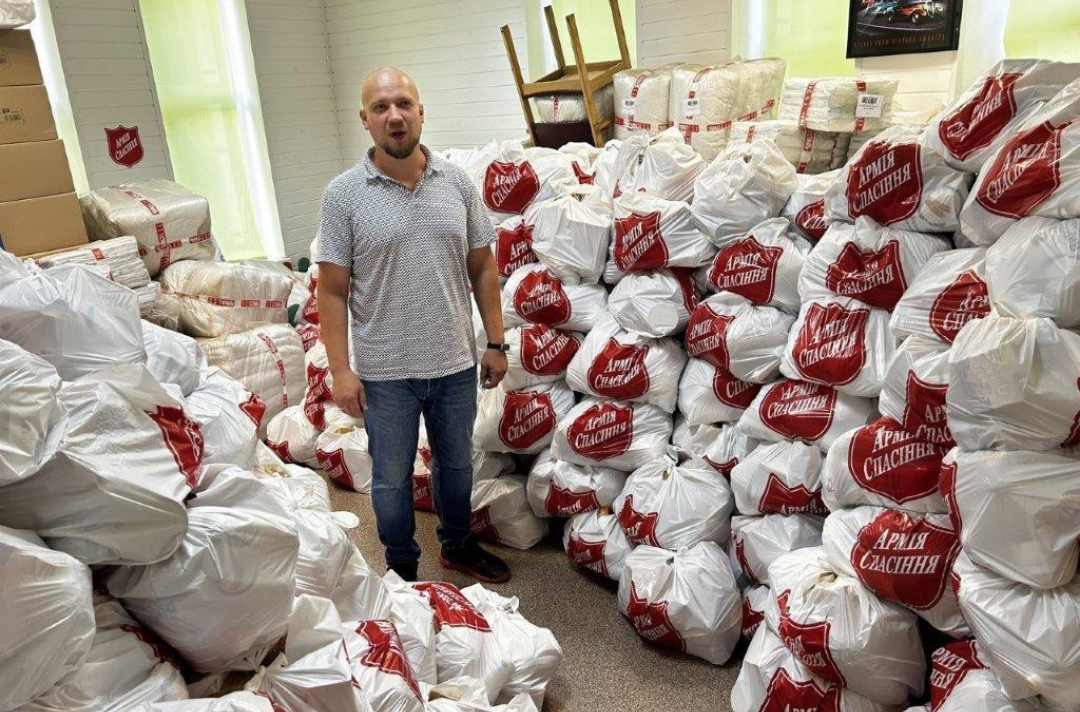 A photo shows someone standing in a room packed to the brim with packages emblazoned with the Salvation Army shield.