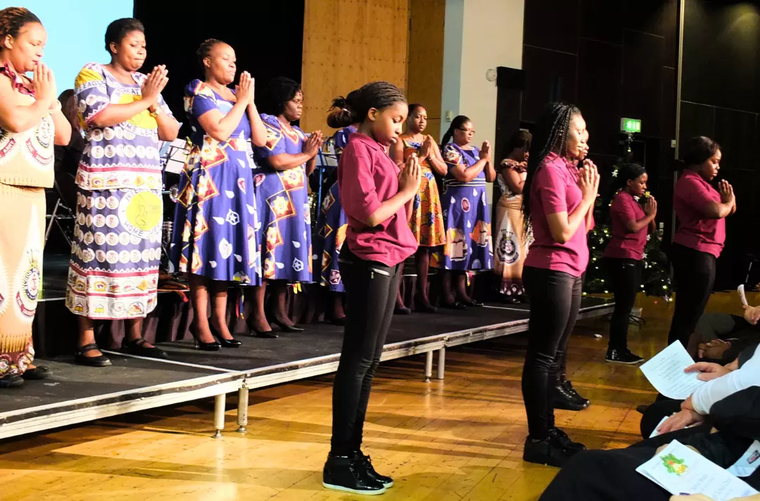A photo shows people standing on the platform with their hands clasped and their heads bowed in prayer.