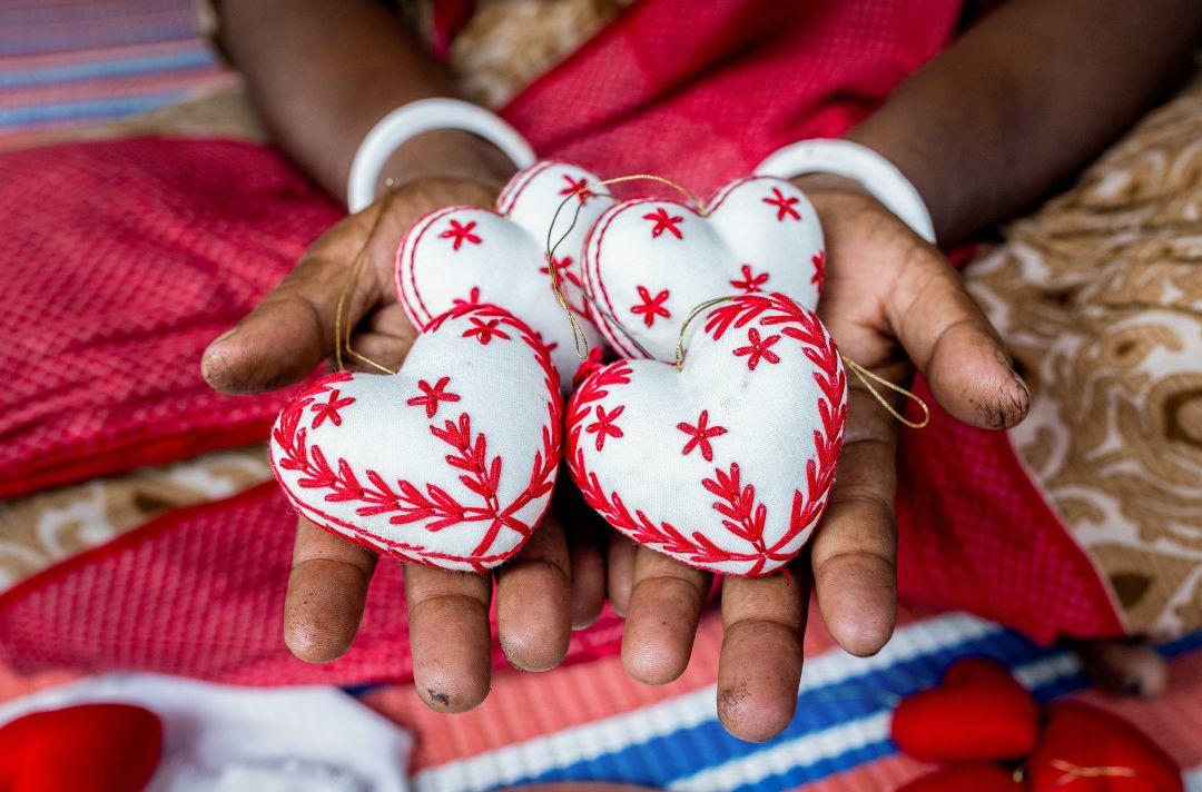 A photo of hands holding handmade heart baubles
