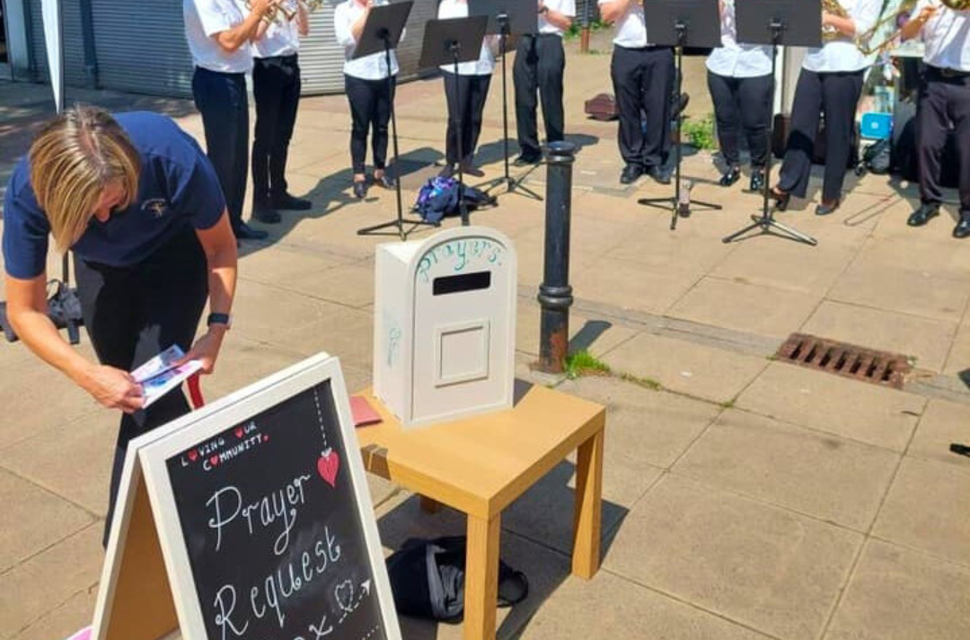 A photo shows Sale Band out with the corps prayer box.
