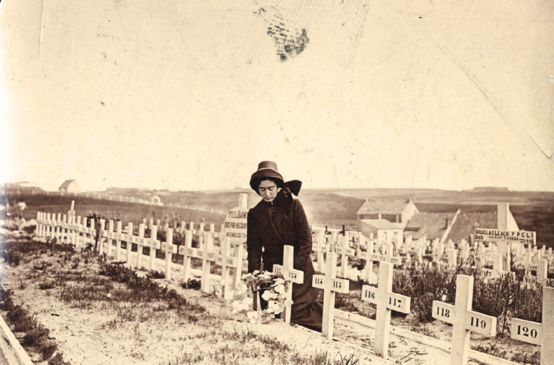 An old black and white photo shows a Salvationist placing flowers at a war grave.