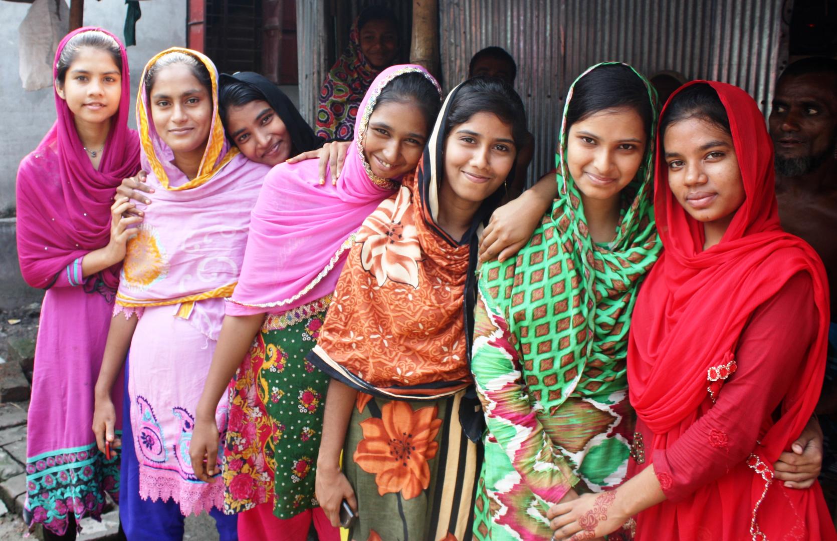 A row of smiling women wearing saris.