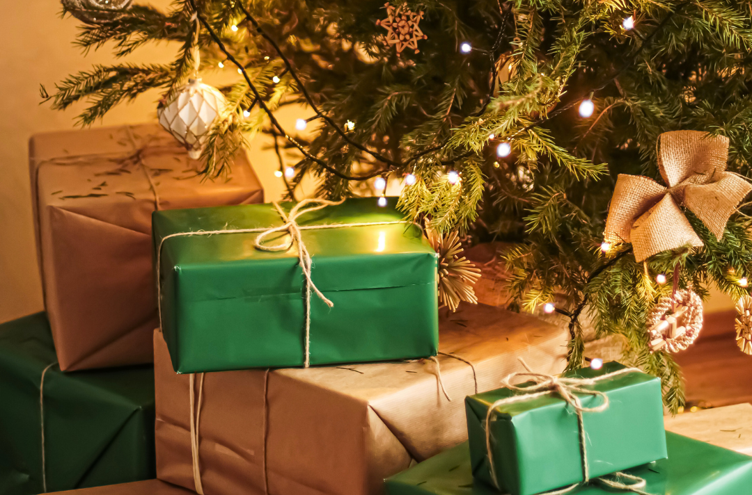 A photo shows Christmas presents wrapped in brown and green paper under a Christmas tree.