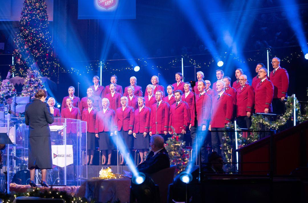 A photo of the International Staff Songsters singing at the Royal Albert Hall in red Salvation Army uniforms