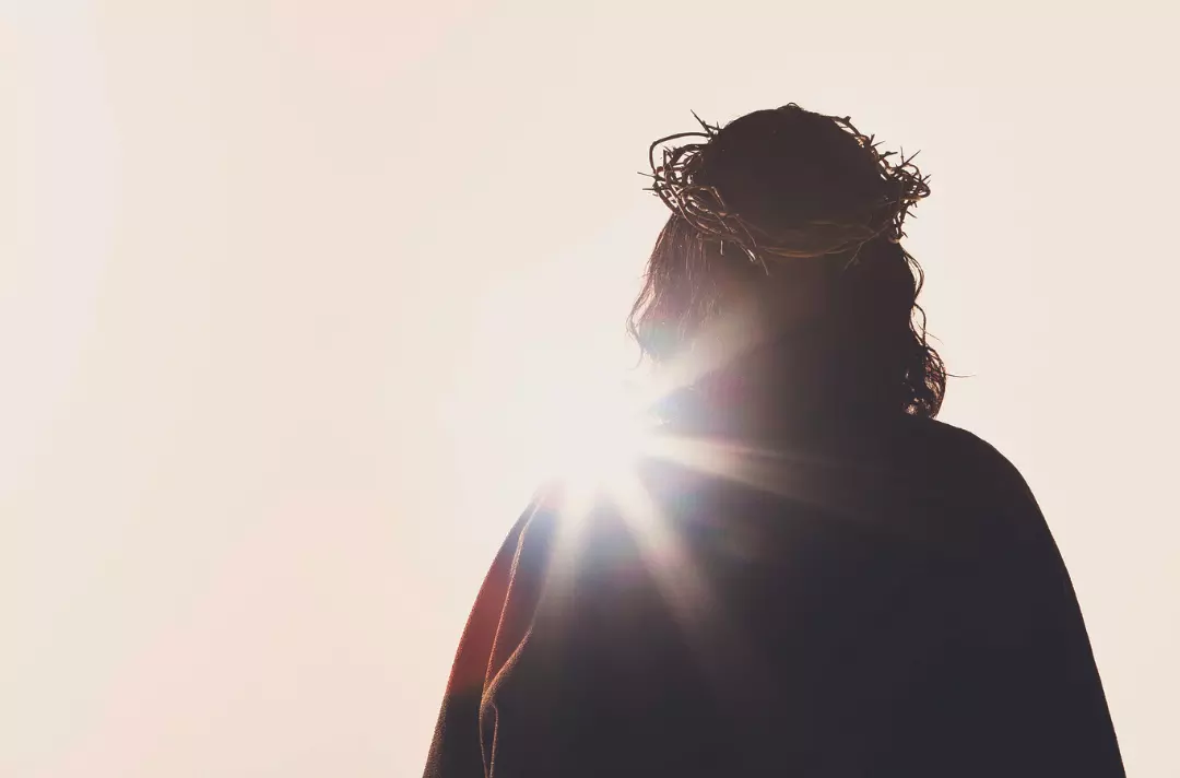 A photo shows adult Jesus wearing a crown of thorns and silhouetted against a murky sky.