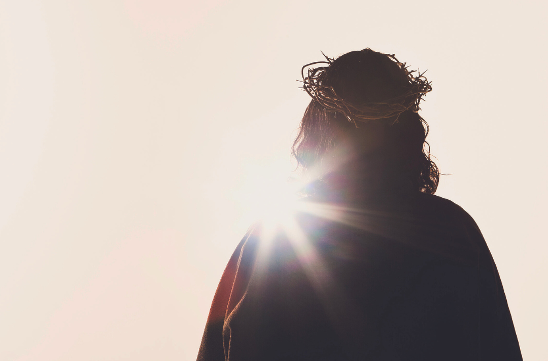 A photo shows adult Jesus wearing a crown of thorns and silhouetted against a murky sky.