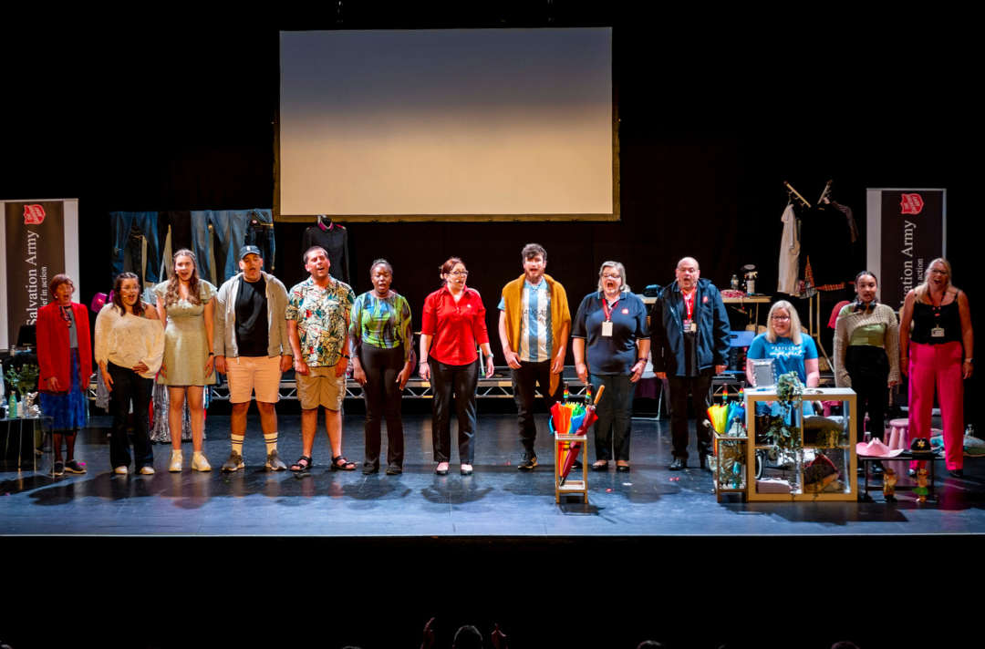 A photo of the Belongings cast singing on stage