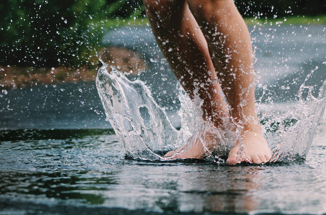 A photo shows someone jumping into a puddle with bare feet.