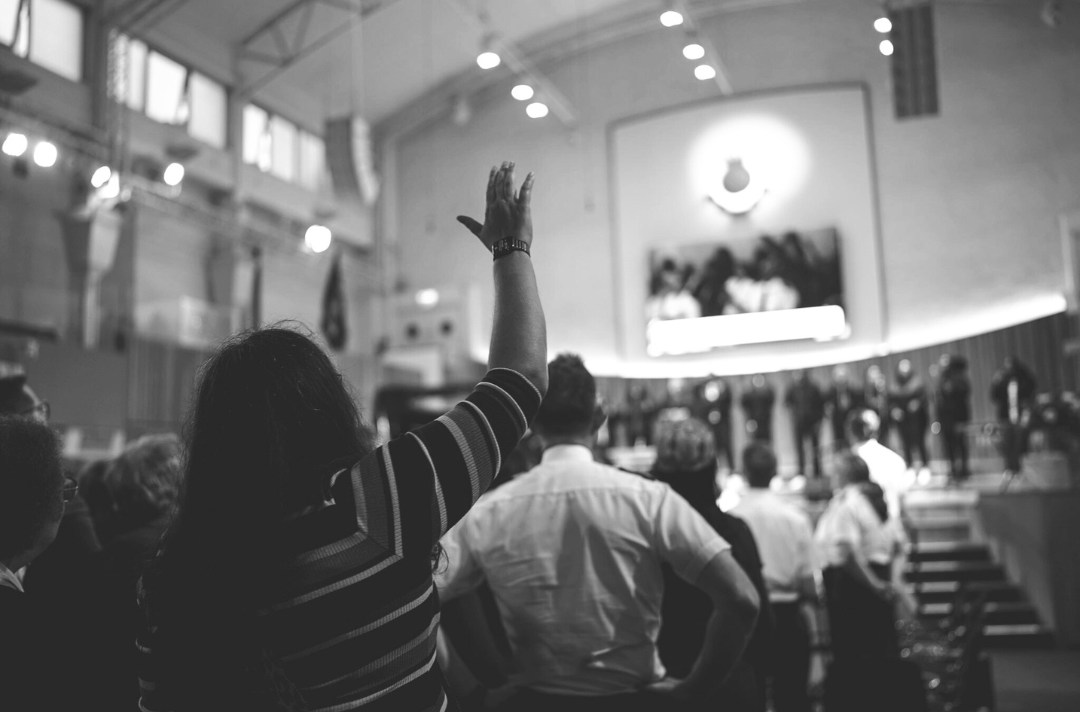 A modern black and white photo shows people worshipping in a Salvation Army hall.