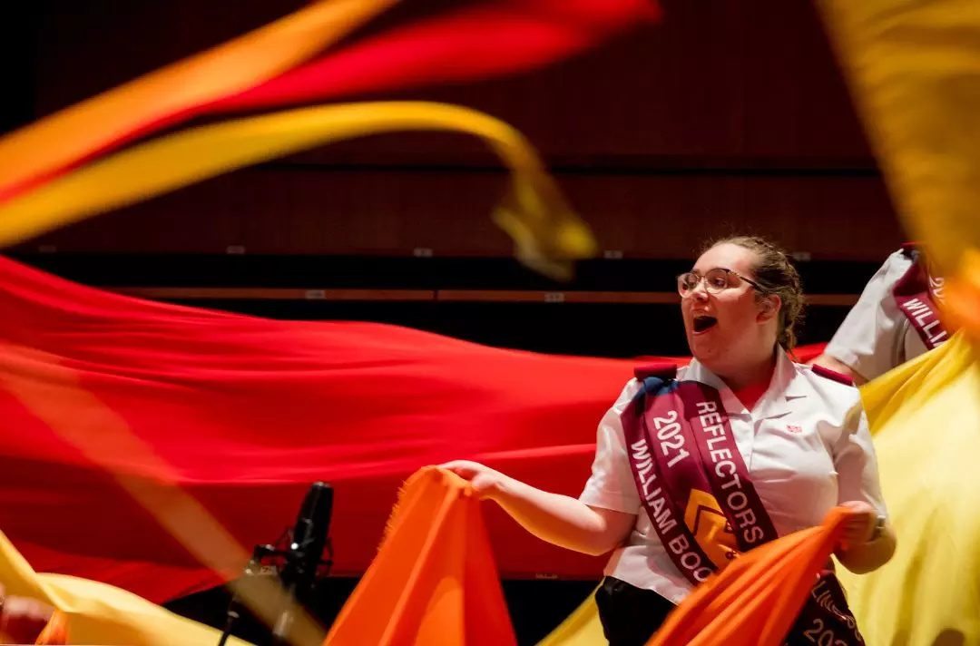A photo of a newly commissioned Salvation Army officer wearing uniform. She is singing and waving flame-coloured materials during at the Together 2023 weekend.