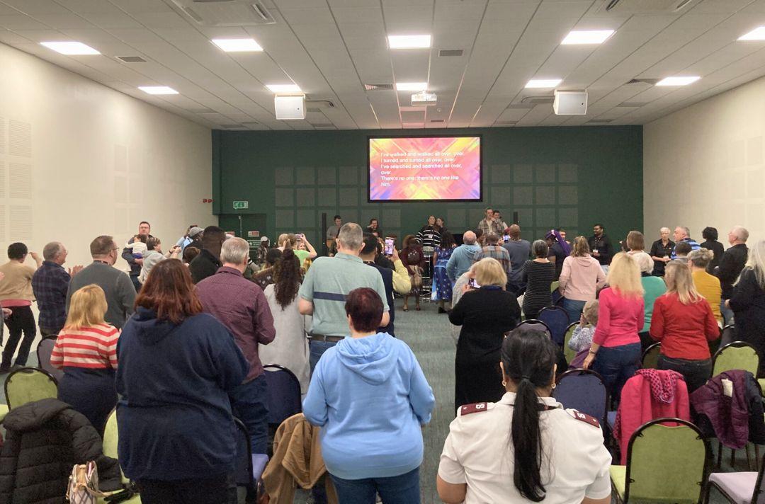 A photo shows a large crowd of people engaging in worship.