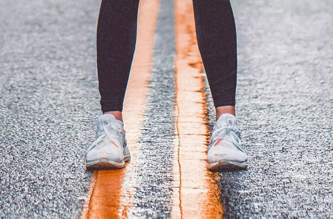 A photo shows a pair of legs standing astride two yellow lines.