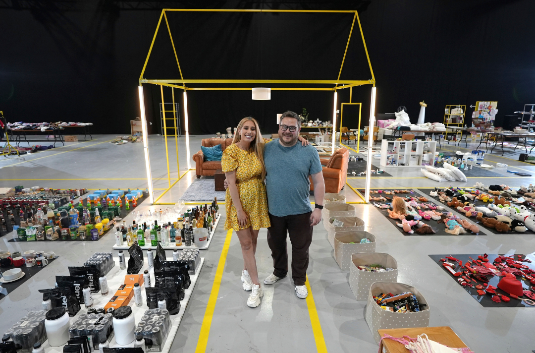 A scene from Sort Your Life Out shows two people standing in a warehouse filled with belongings. Picture: BBC/Optomen Television/Neil Kent