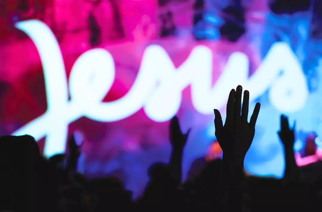 A photo shows people worshiping with hands raised. A giant neon-style sign reading 'Jesus' is out of focus in the background.