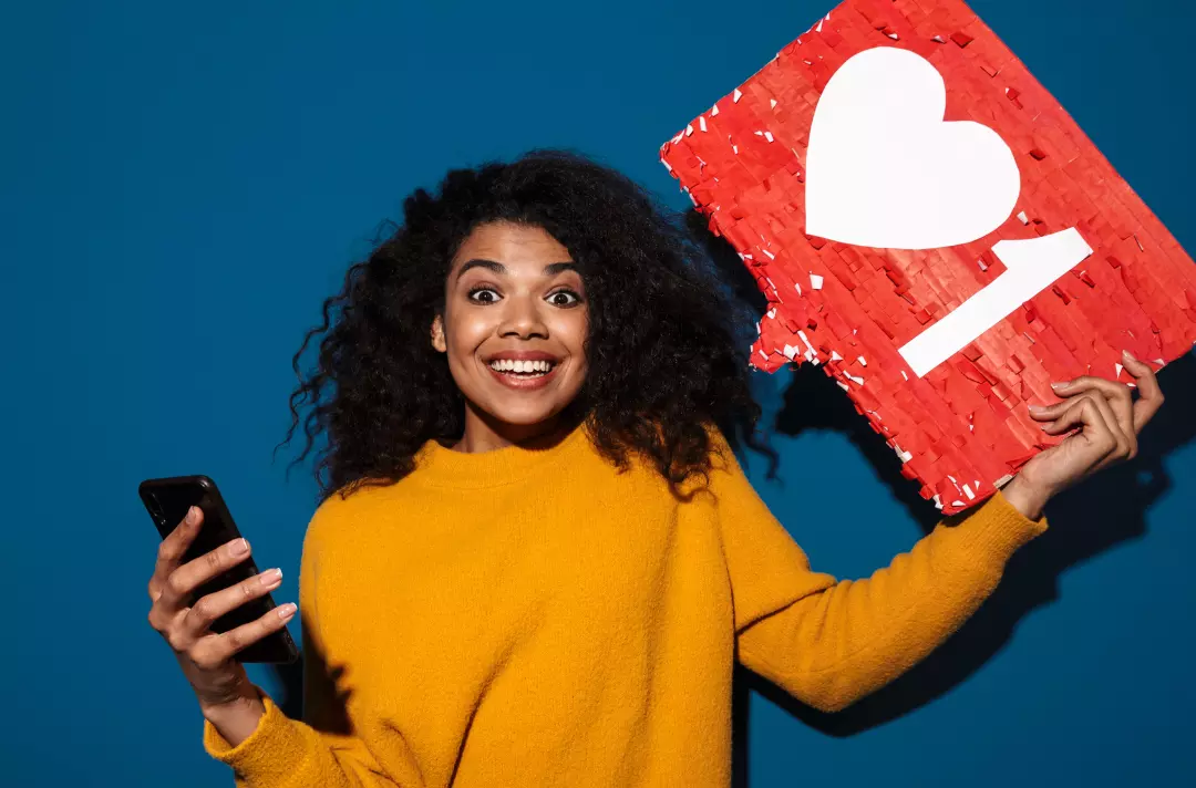 A photo shows a person looking at the camera while holding a mobile phone and a large 'like' symbol.