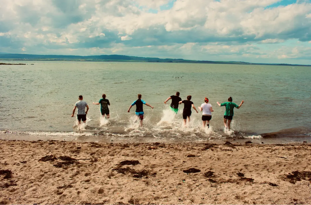 A photo of young adults running into the sea