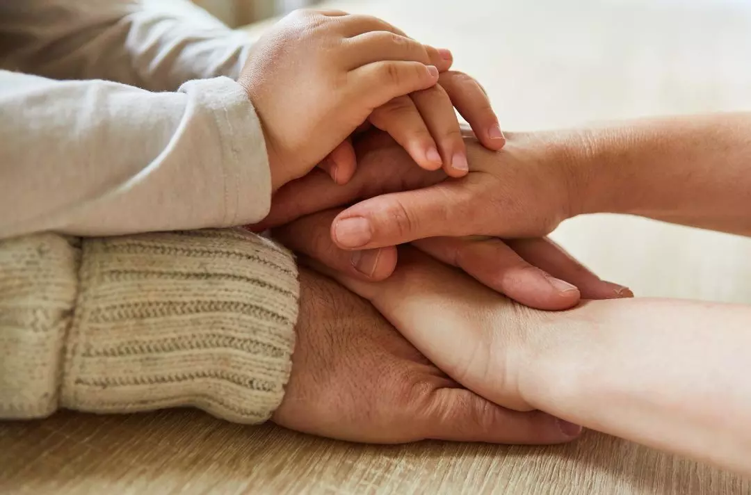 A photo of hands from people of different ages piled on to of one another