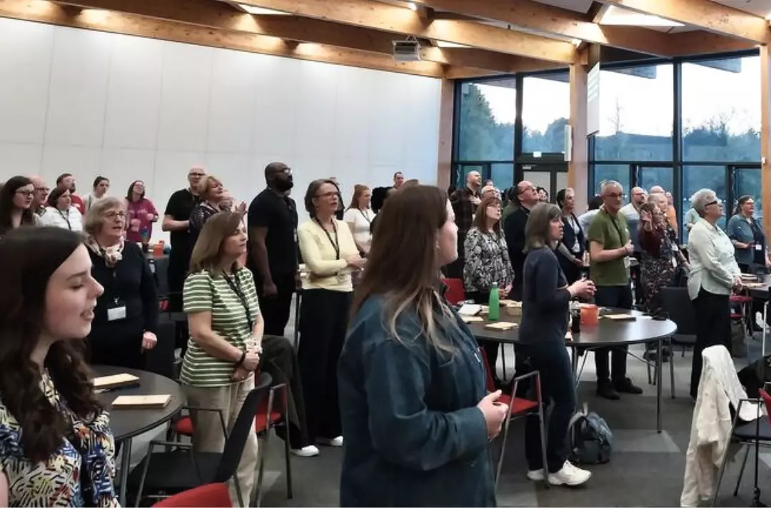 A photo shows people worshipping in a large, airy room.