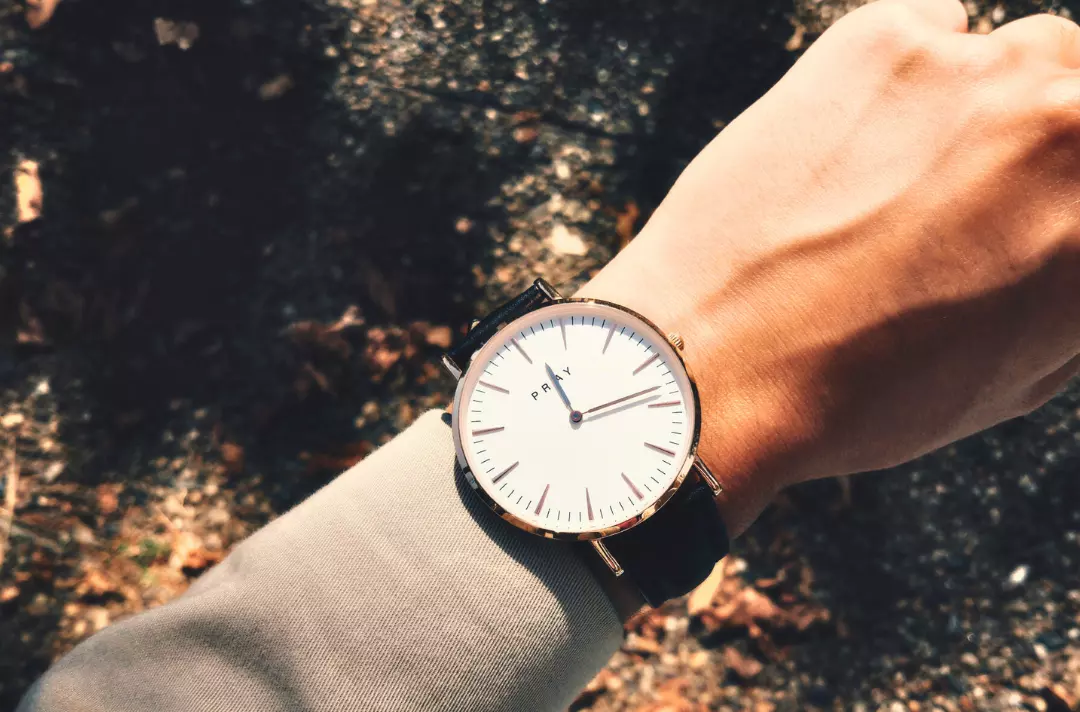 A photo shows a watch on a wrist. The face of the watch displays the word 'pray'.