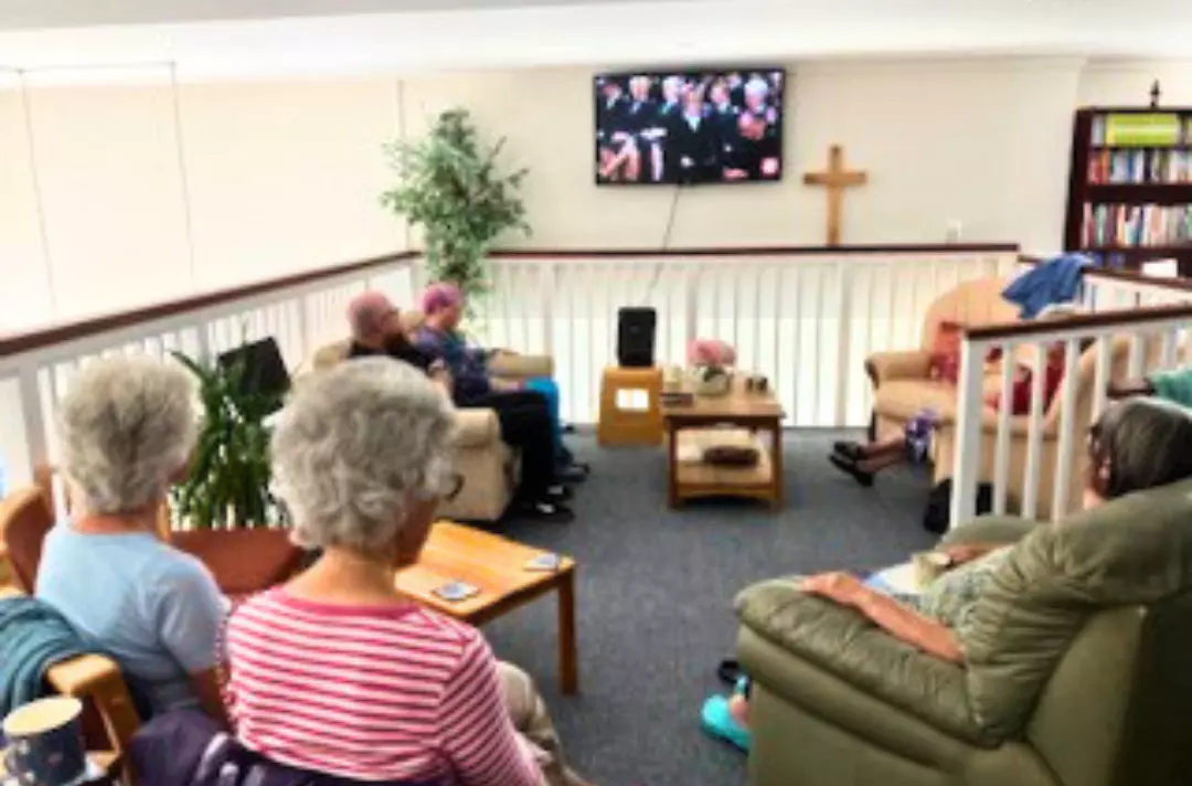 A photo shows people sat in a small group on the mezzanine of a charity shop.