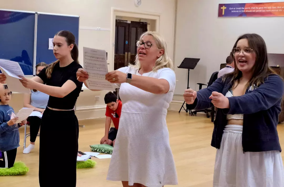 A photo shows three people rehearsing for Take a Stand.
