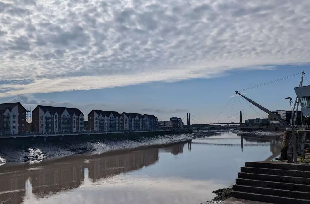 A photo of the river front in Newport. The sun is shining through dappled cloud.