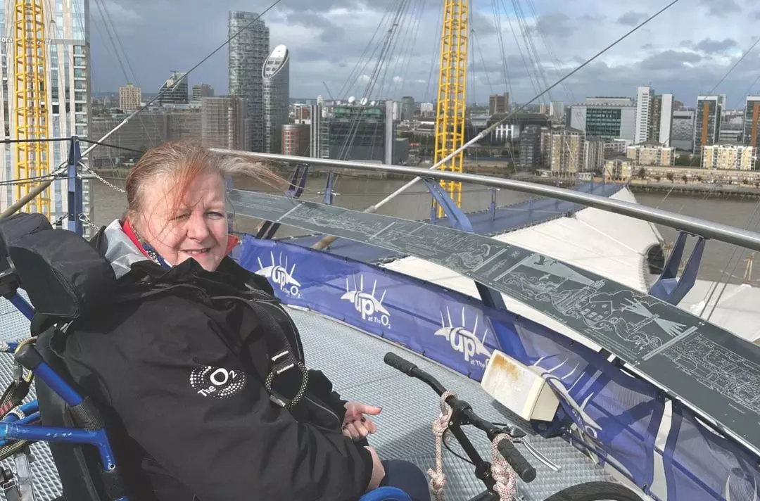 A photo of Angela Daymond in her wheelchair on top of the O2 in London