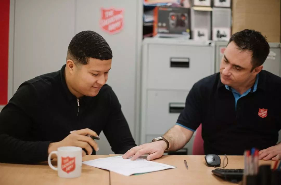 A photo of a Salvation Army volunteer helping someone with paperwork