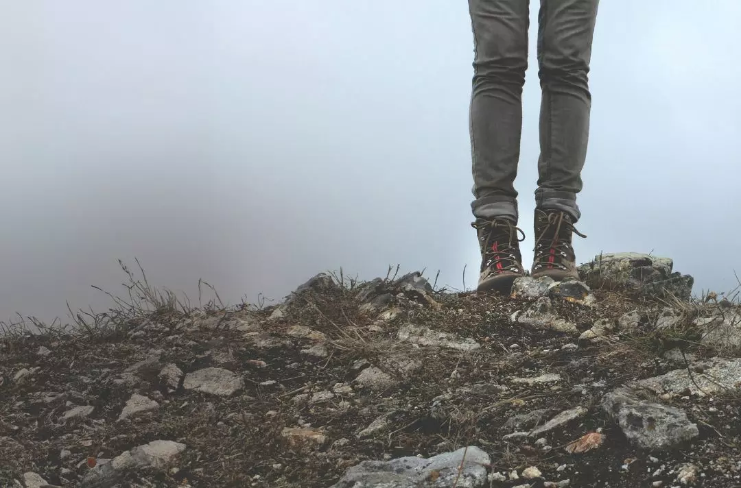 Photo of a hiker's booted feet standing on a rocky outcrop