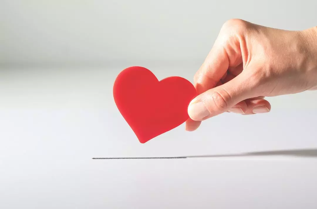 A photo of a hand holding a red paper heart
