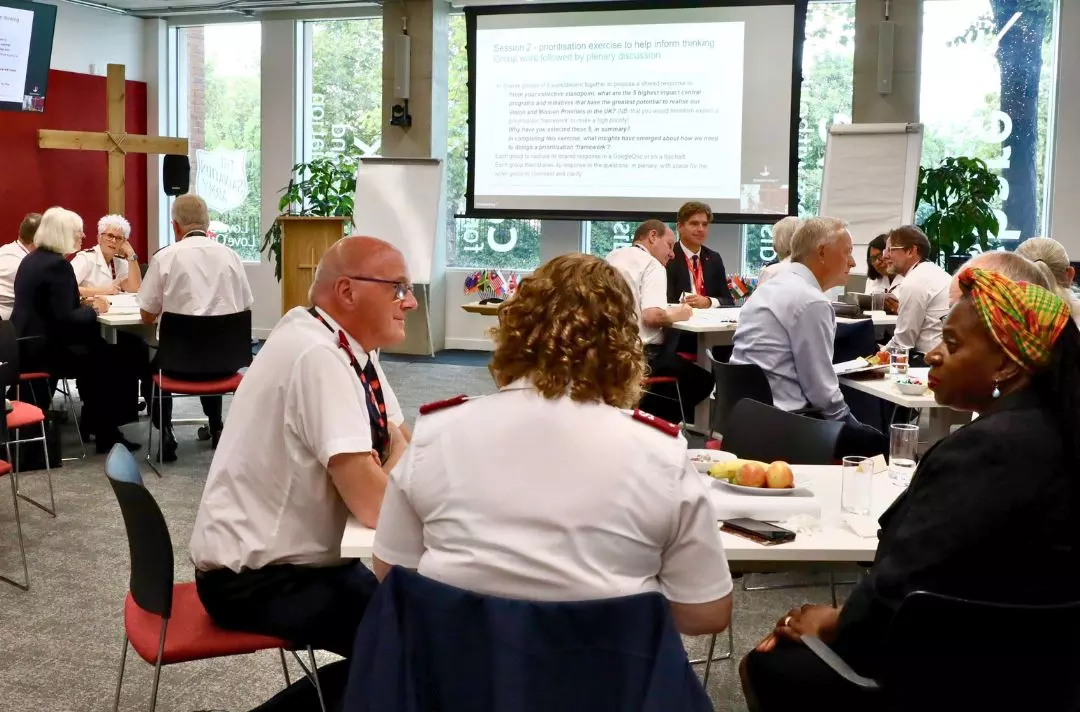 A photo shows people sat around tables in discussion.