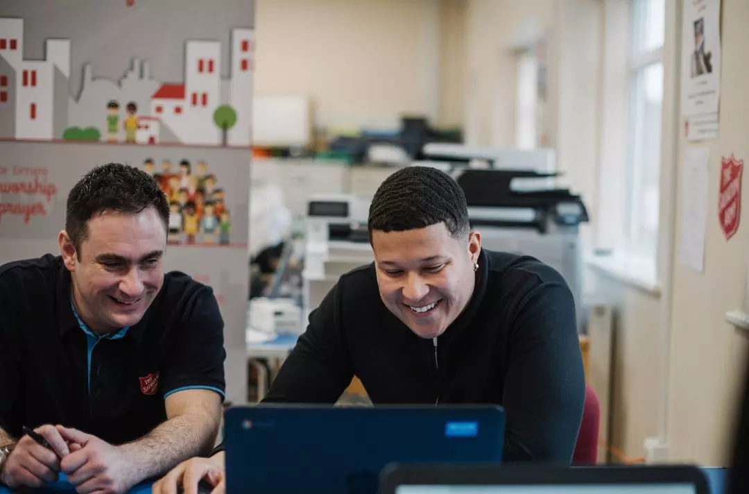 A photo of a Salvation Army employee helping someone fill out a form on a computer