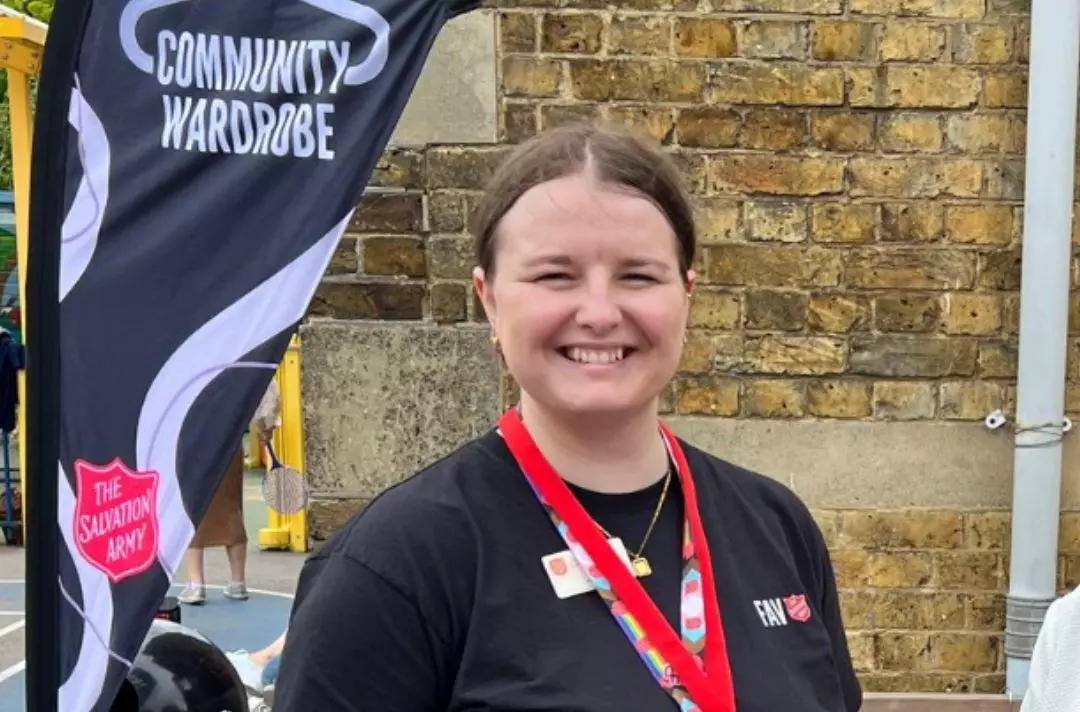 A photo of a Salvation Army leader in front of their uniform exchange stall called Community Wardrobe