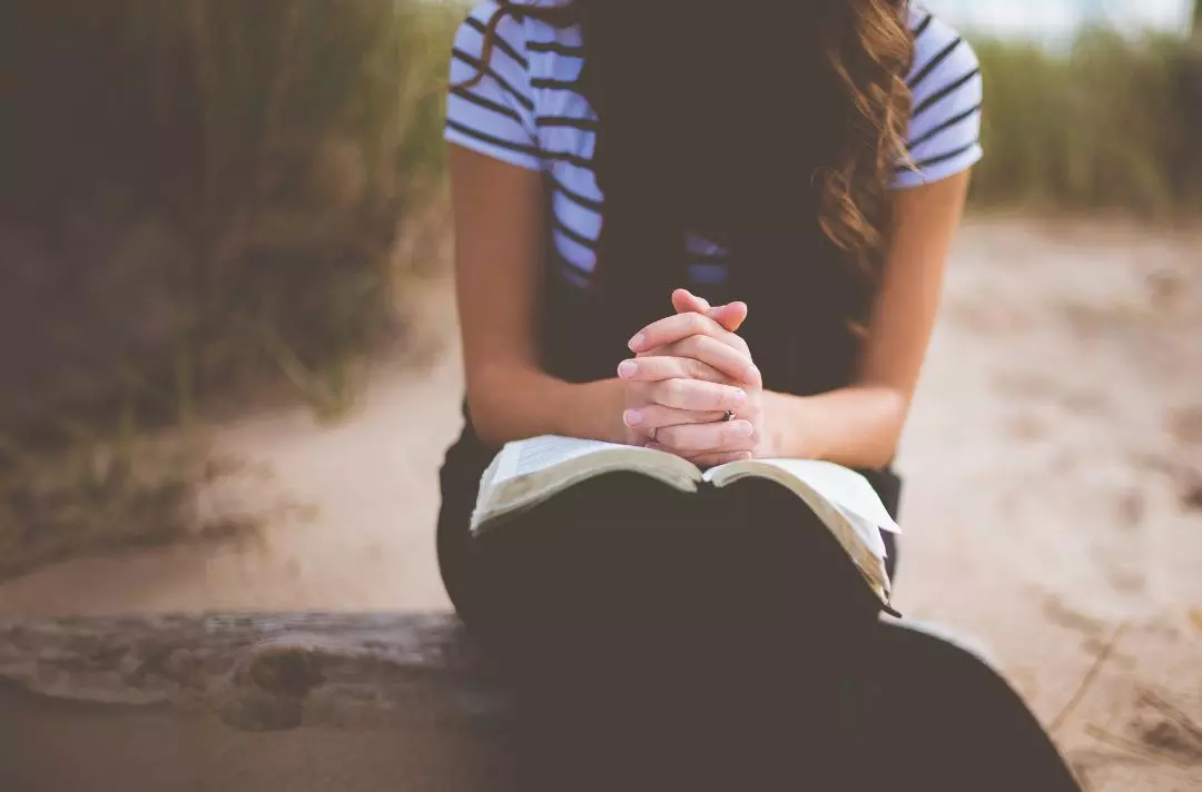 A woman prays over a Bible