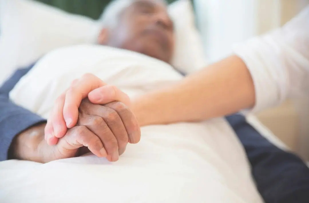 A photo of someone holding an elderly patient's hand