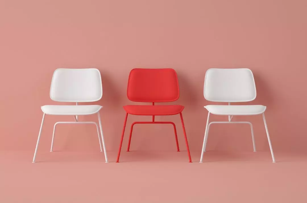 A photo shows three chairs, one red and two white either side.
