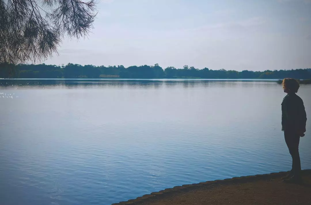 A photo of a person looking across a calm lake
