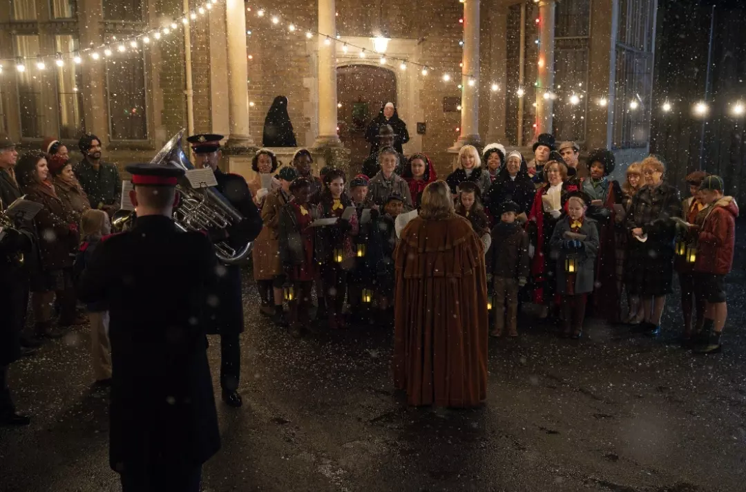 A scene from Call the Midwife shows people singing while a Salvation Army band plays.