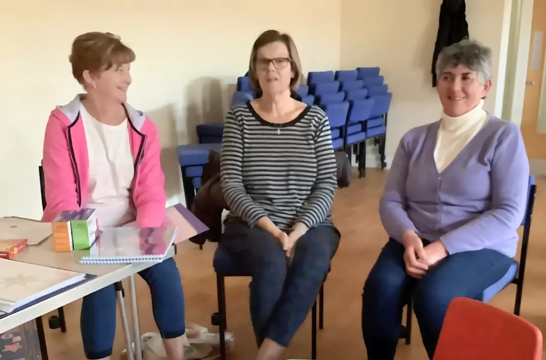A photo shows three people sat in discussion.