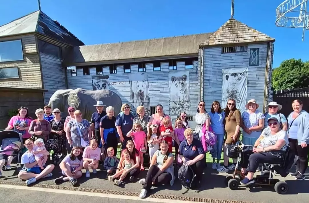 A photo shows a large group of people posing for a photo during a day out.
